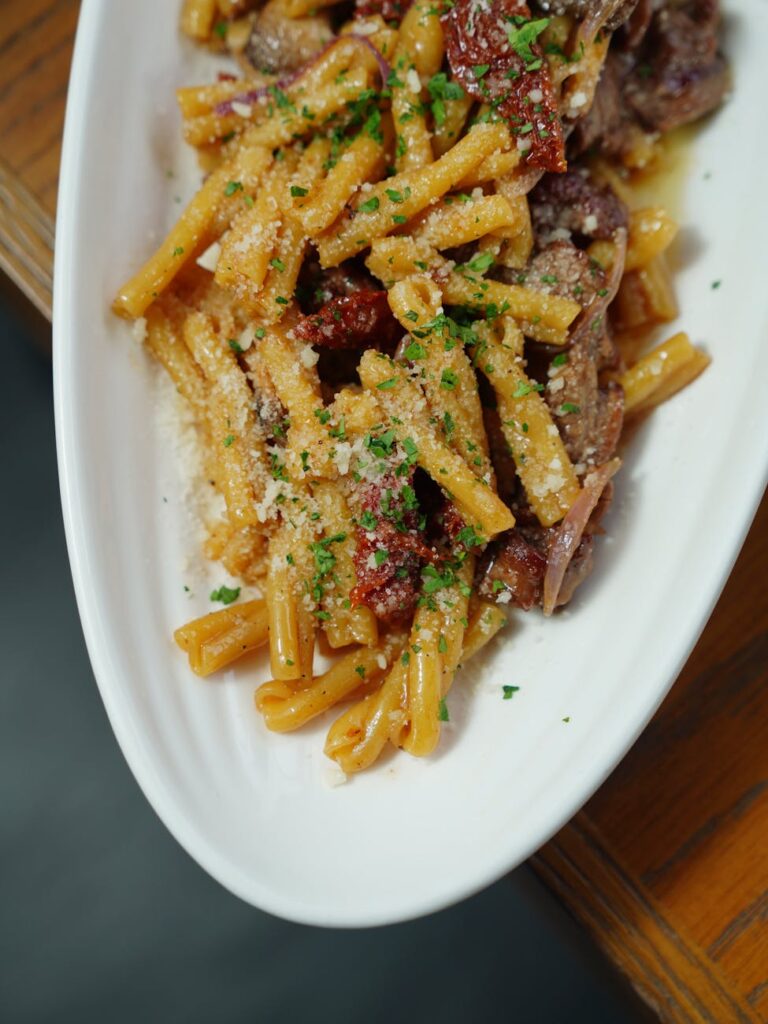 casarecce pasta with meat and dried chili sprinkled with grated cheese and chopped basil