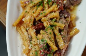 casarecce pasta with meat and dried chili sprinkled with grated cheese and chopped basil